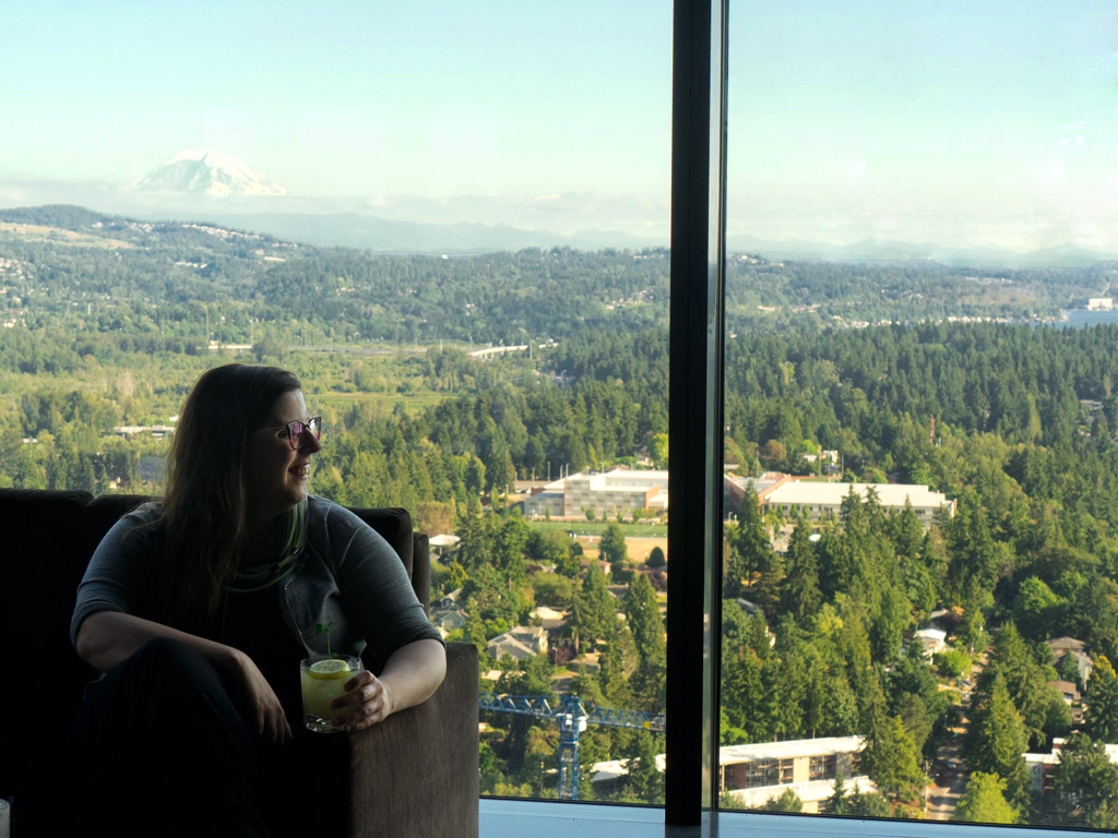 woman looking out glass window from rooftop restaurant, one of the best restaurants in Seattle with a view