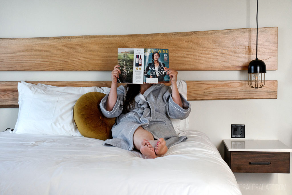 woman reading a magazine in bed at a Eugene boutique hotel