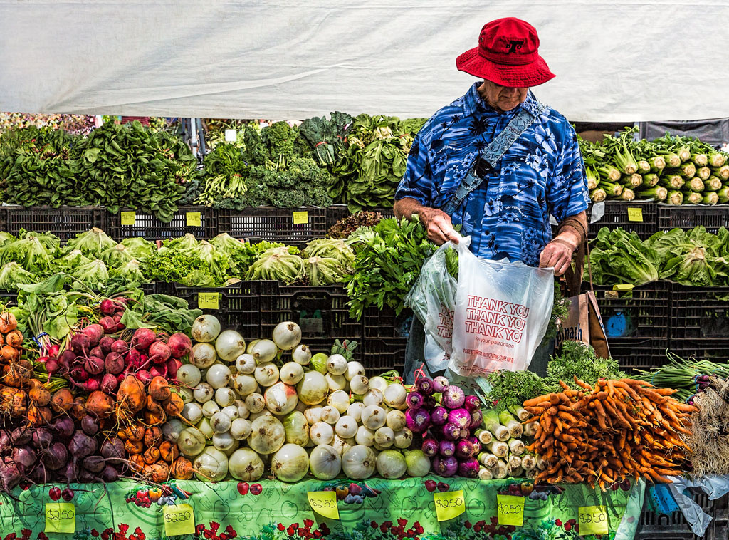 man selecting produce at a farmers market