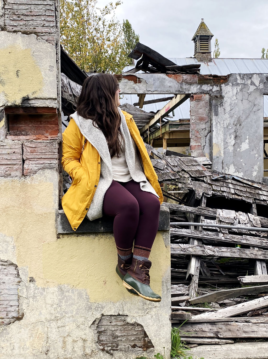 woman sitting on a decrepit ledge of an abandoned asylum building in disrepair | Best Road Trips from Seattle