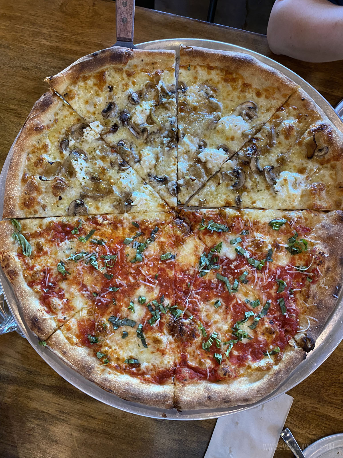 overhead shot of a pizza split half red sauce, half white sauce