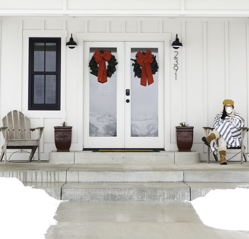 woman sitting on porch in snow at one of the best winter cabins in Washington state