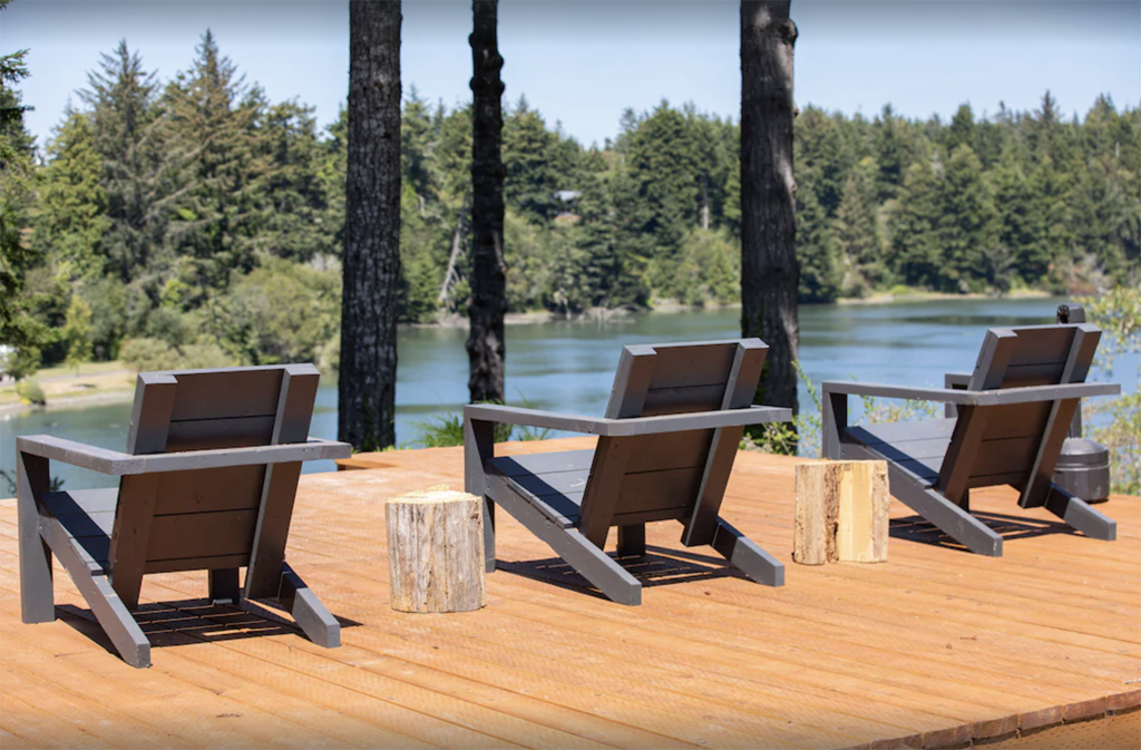 Adirondack chairs on a deck overlooking a river at one of the best winter cabins in Oregon 