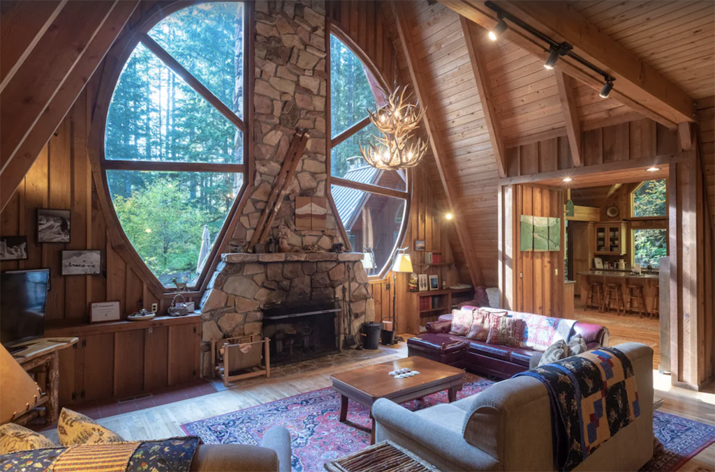 inside a cabin with large geometric windows and a stone fireplace