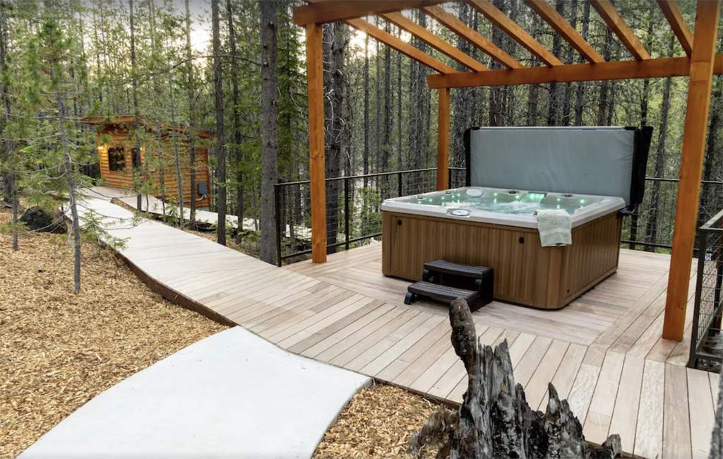 hot tub on a boardwalk with a cabin in background
