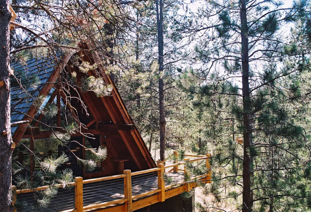 a-frame cabin with a porch tucked in the trees