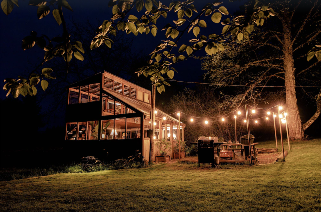 greenhouse cabin with string lights outside at night, one of the best winter cabins in Oregon 