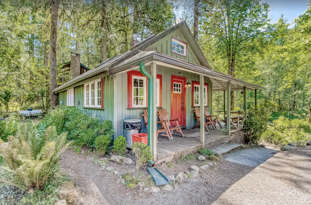 green and red cabin with a front porch