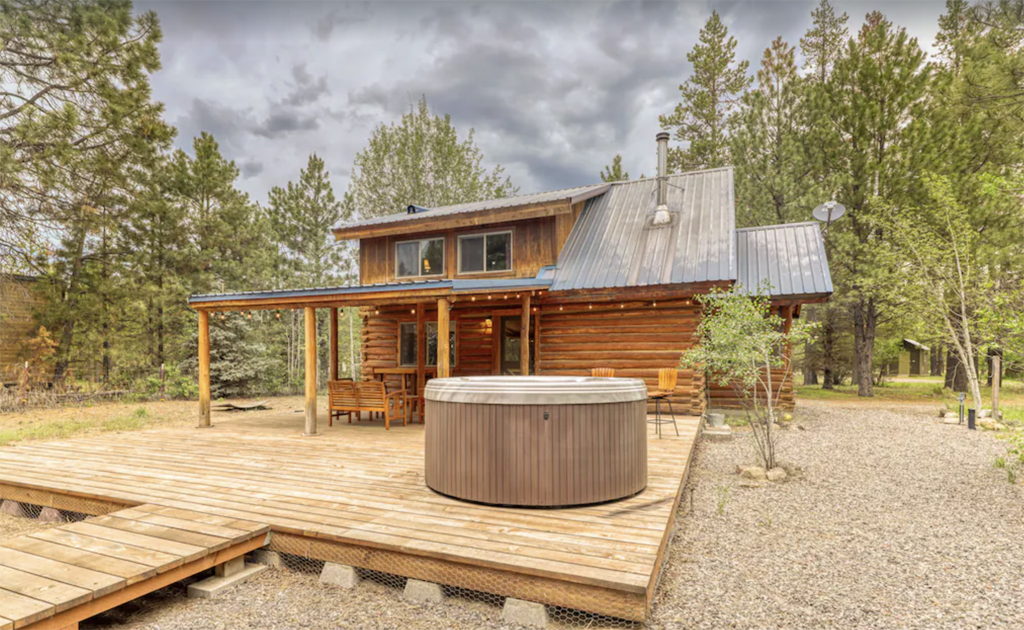 cabin with a large patio and hot tub in the front yard