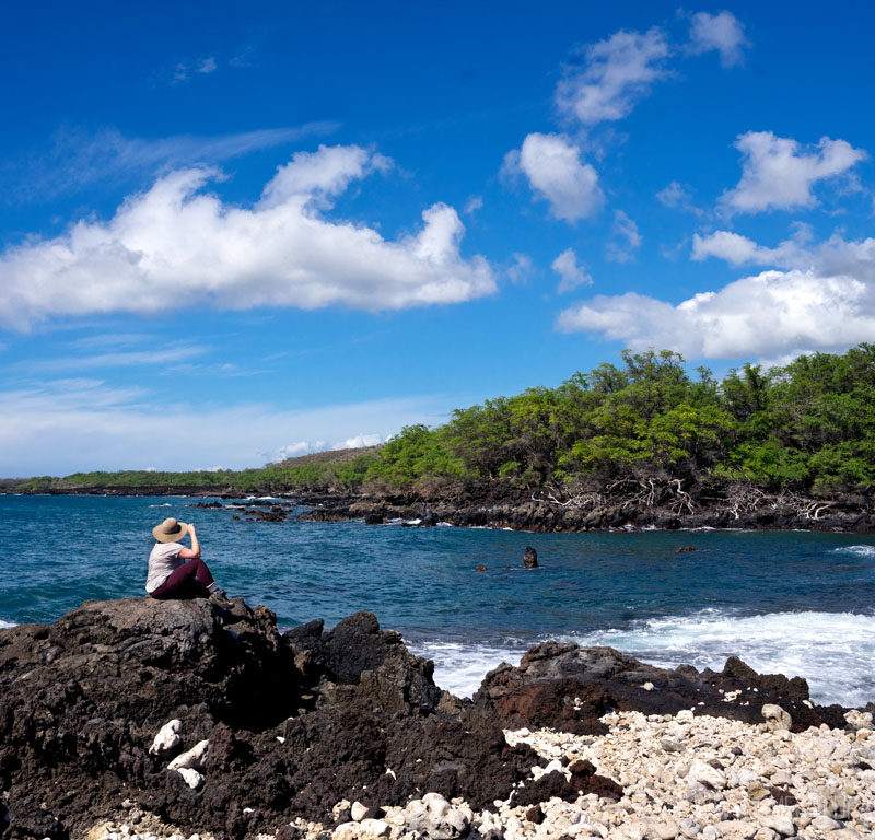 woman overlooking the water on a rocky shore, one of the best hikes on Maui