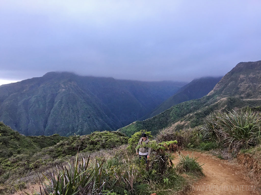 woman walking on an easy hiking trail in Maui with mountains in the distance
