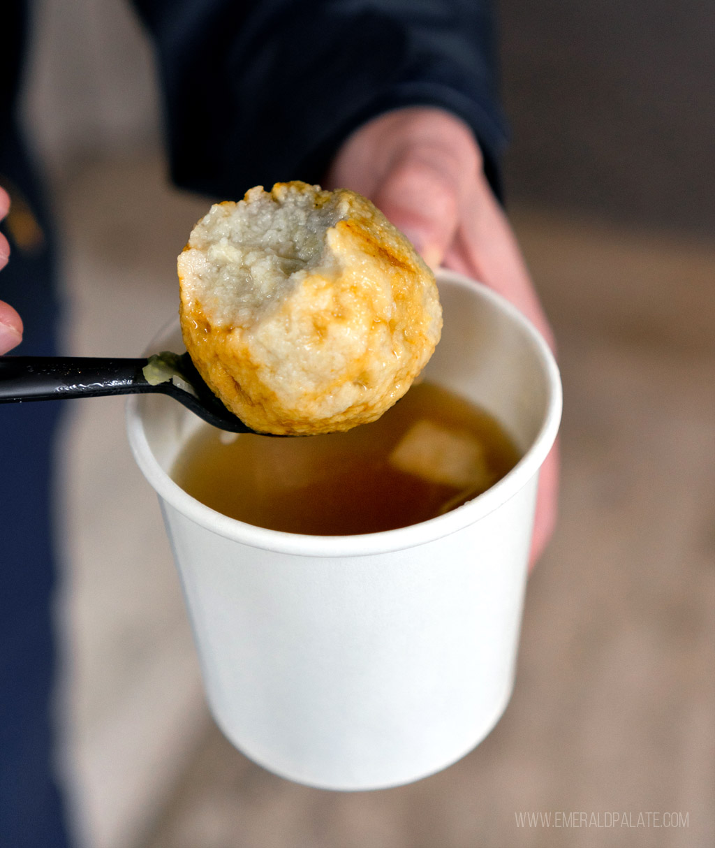 person picking up matzo ball that's been bitten with spoon