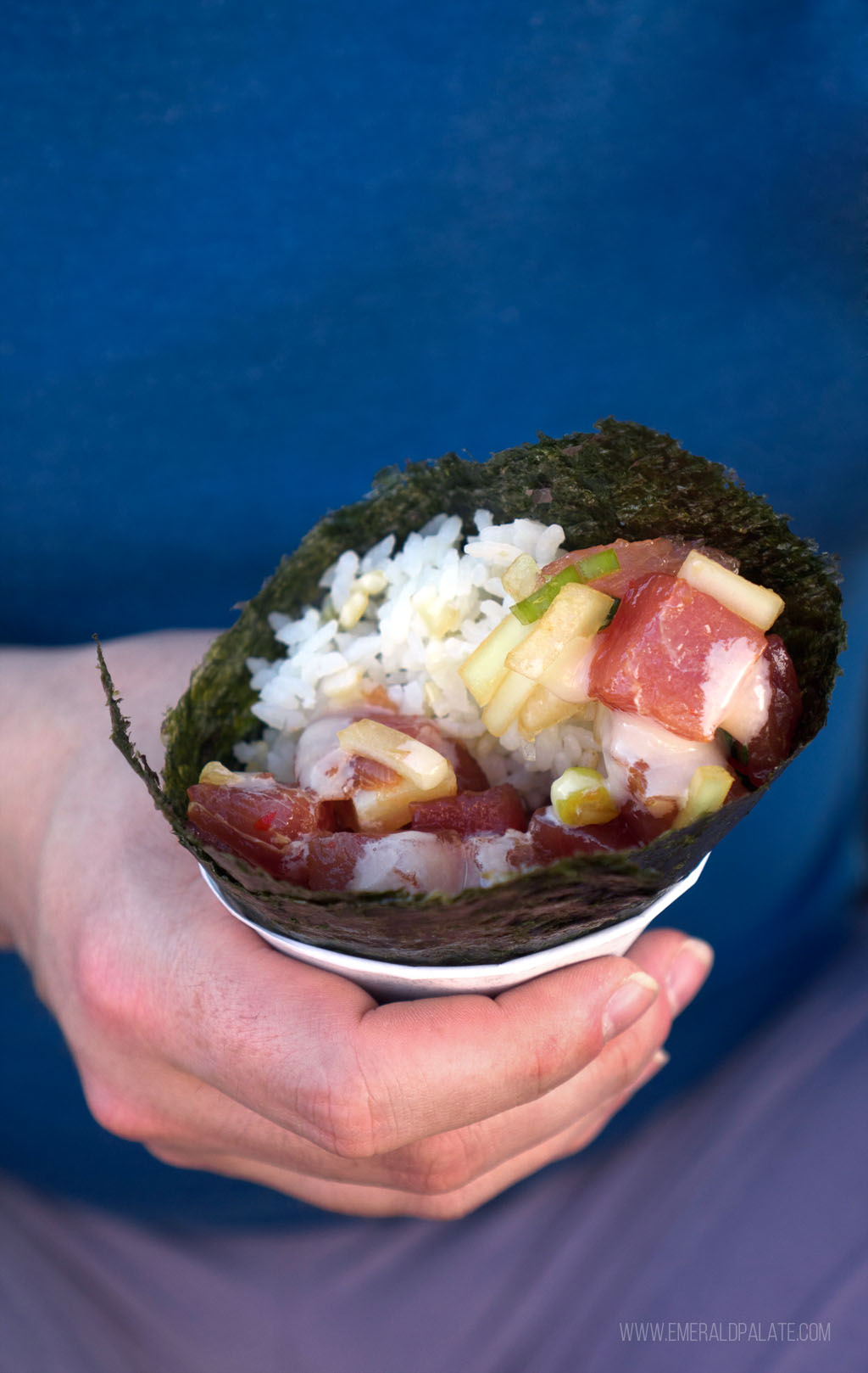 person holding a sushi hand roll