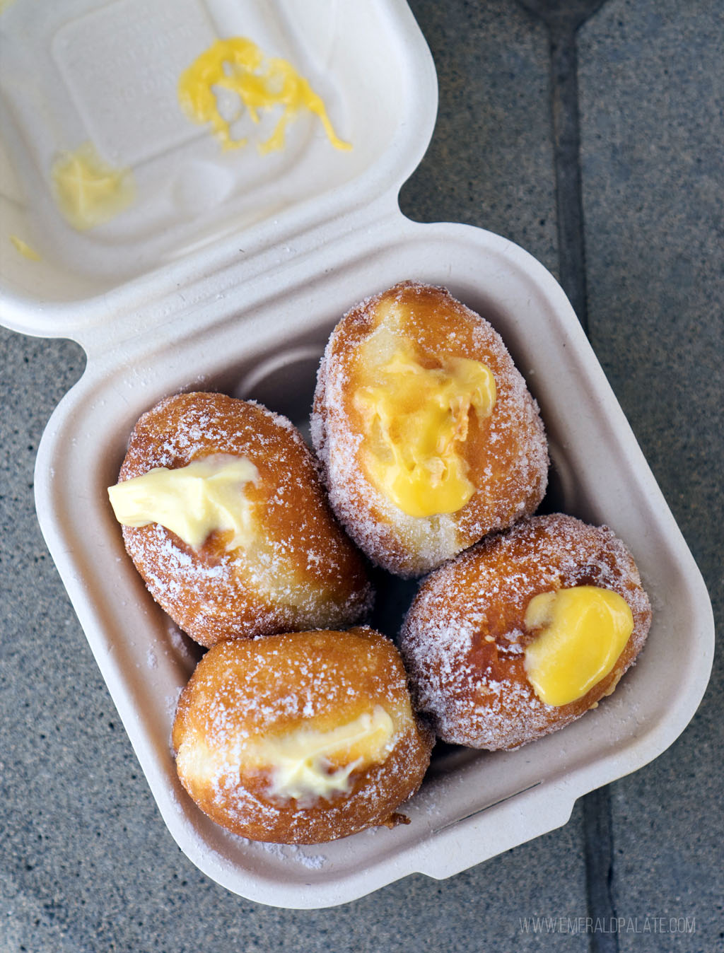 takeout container of cream filled malasadas