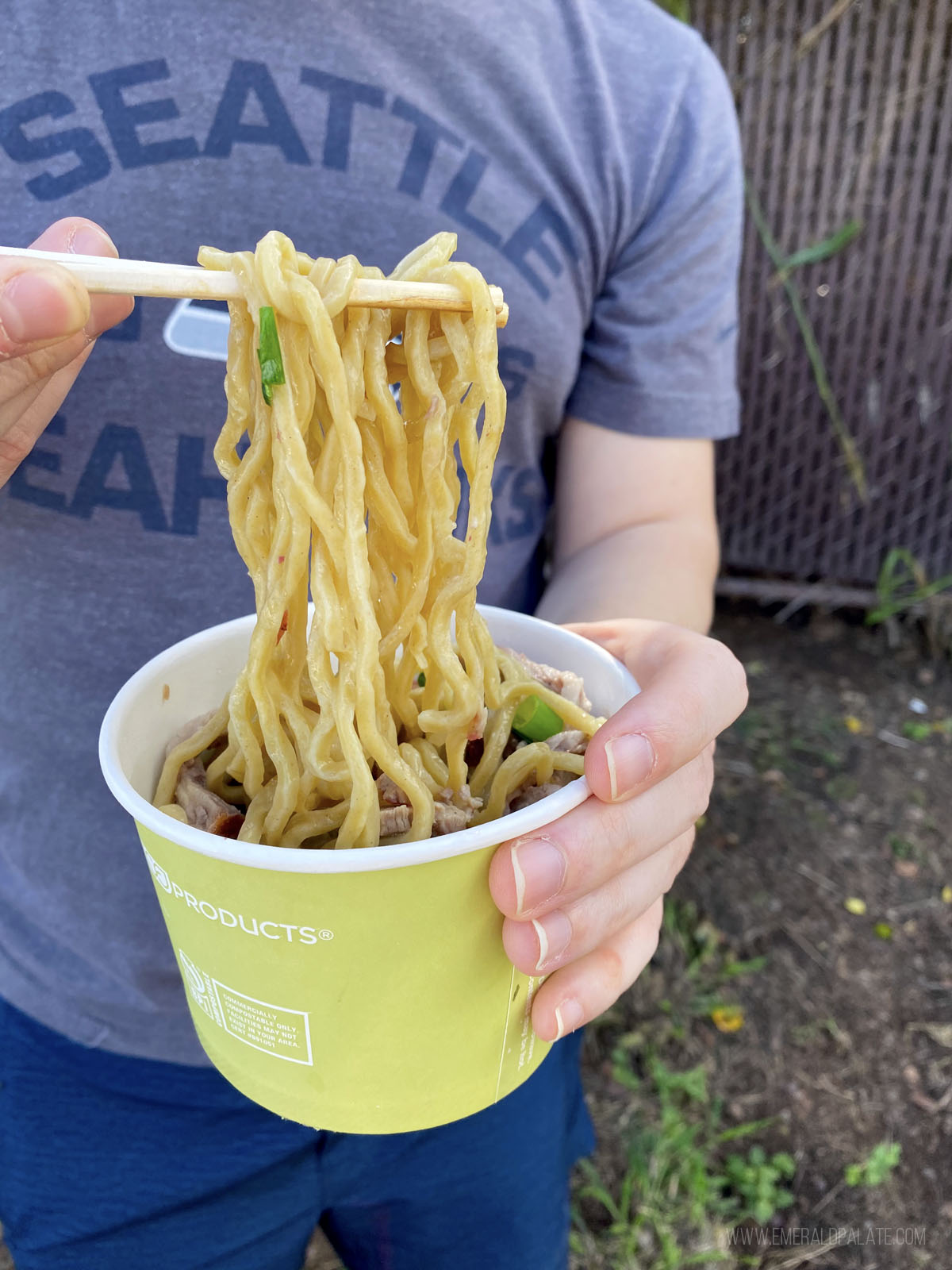 person pulling noodles from a takeout soup container