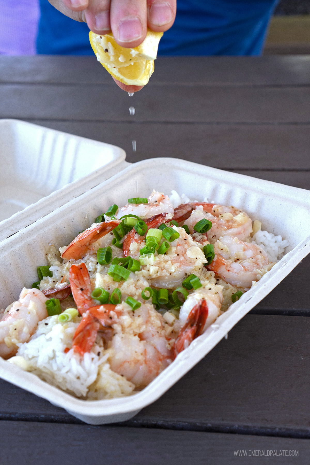 person squeezing lemon over garlic shrimp where locals eat in Maui