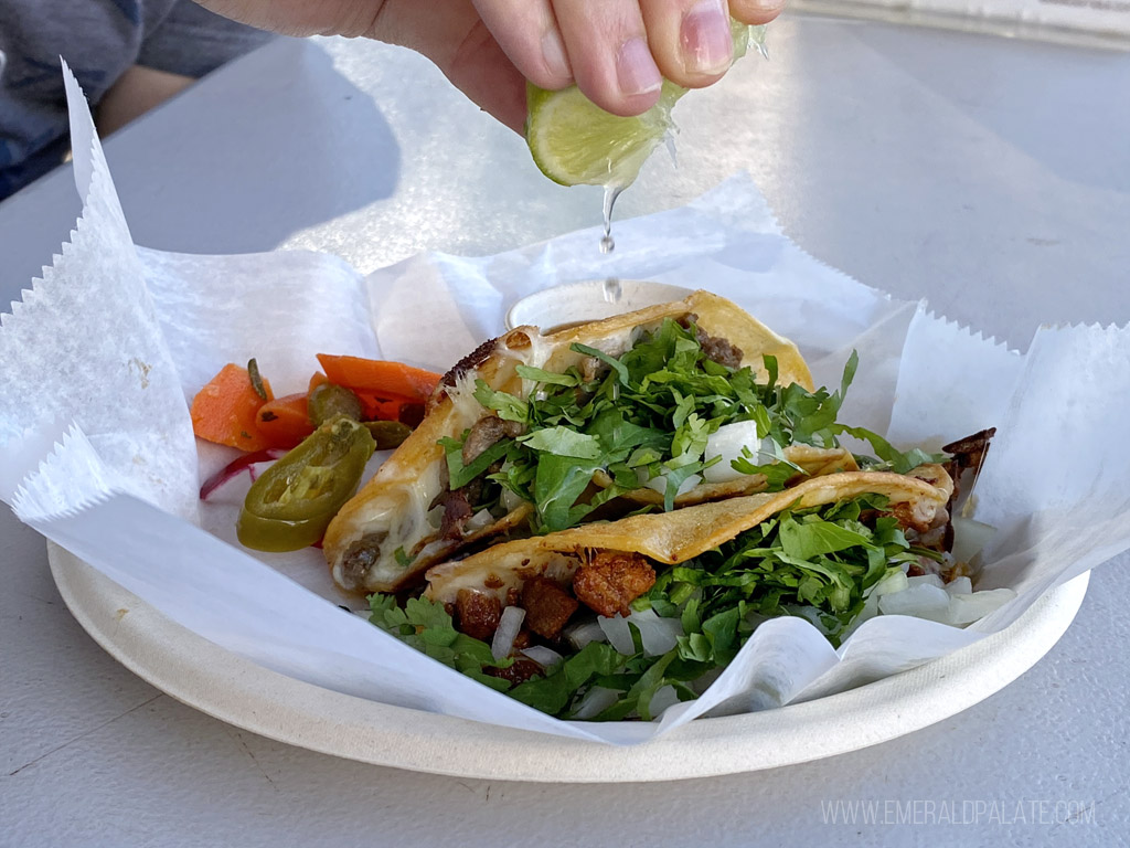 person squeezing lime over tacos from a Mexican food cart in Maui