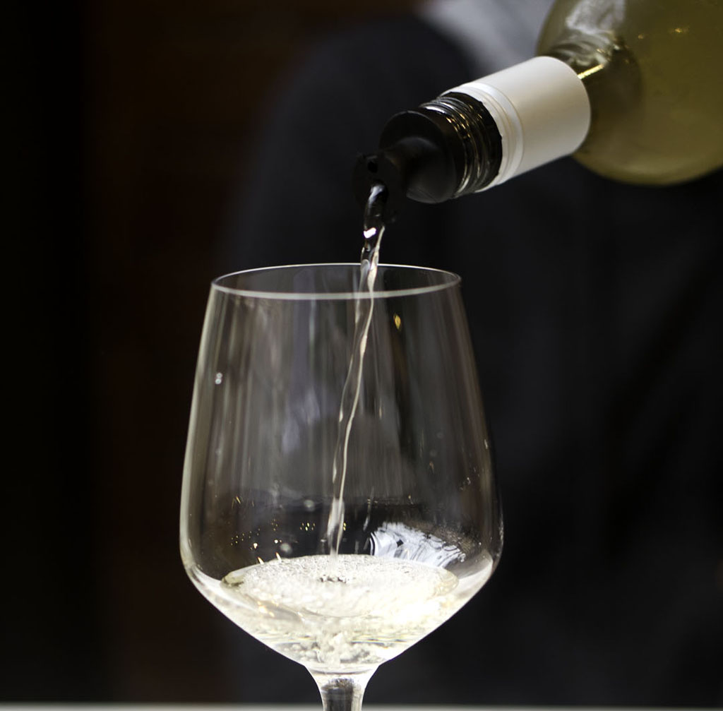 person pouring white wine into a glass