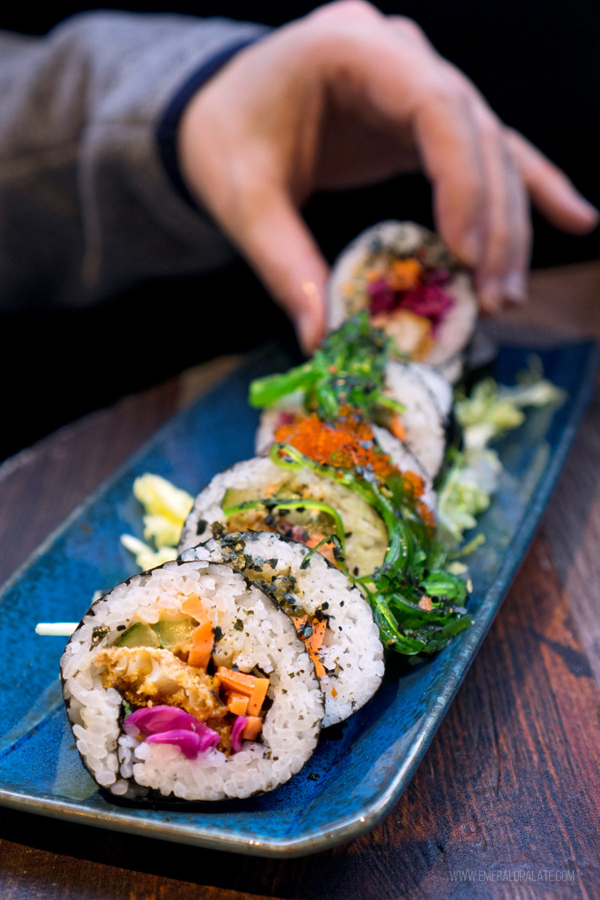 person picking up a sushi roll piece