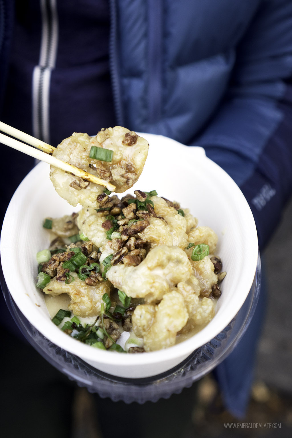 person picking up honey walnut prawns with chopsticks