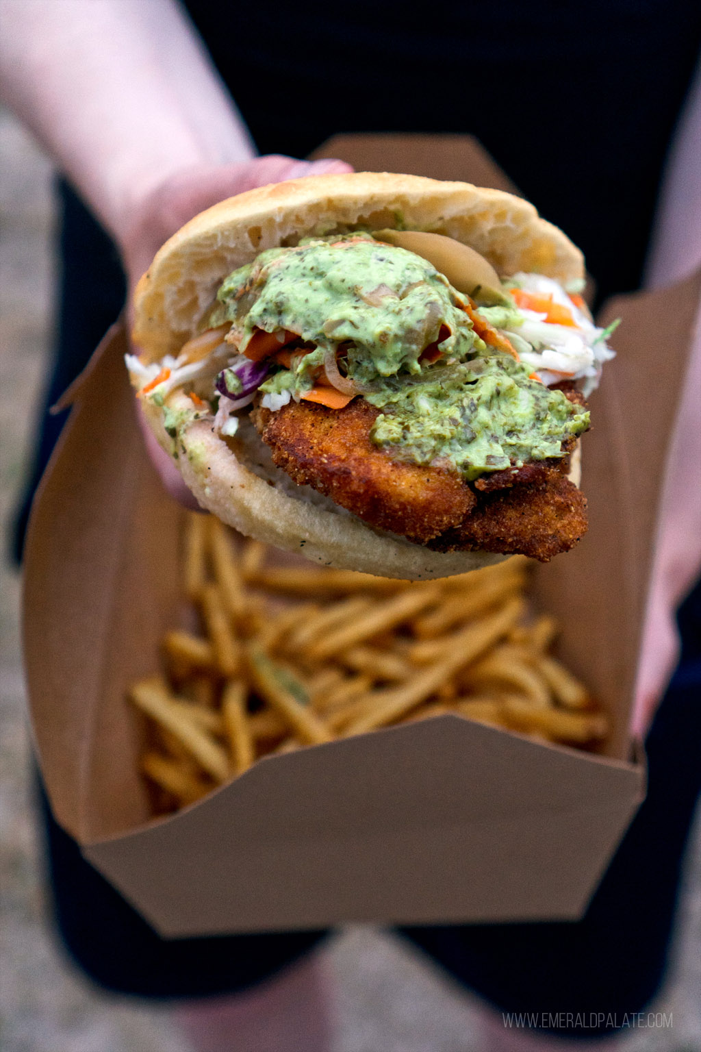 person holding fried chicken sandwich from one of the best Black-owned restaurants in Seattle