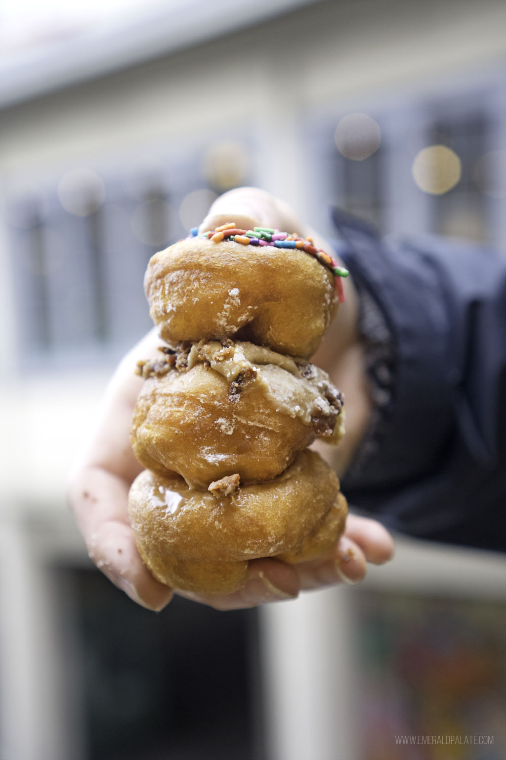 person holding stack of 3 mini doughnuts, some of the best comfort food in Seattle