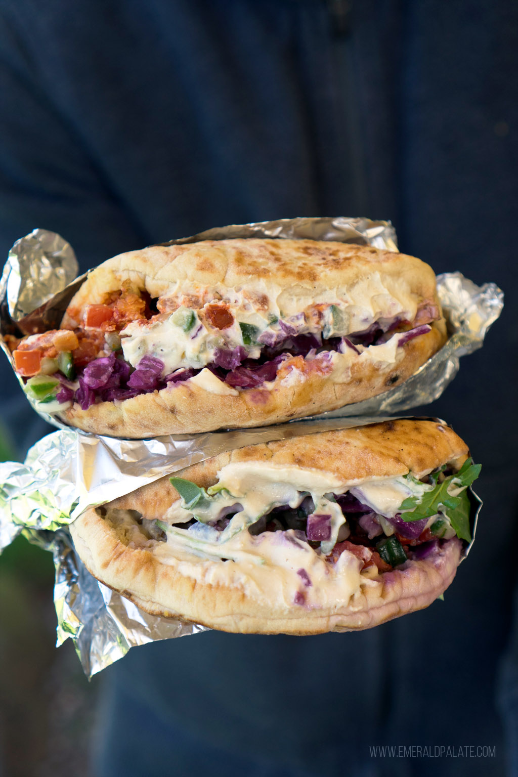 person holding stack of 2 sandwiches from a Seattle Mediterranean restaurant