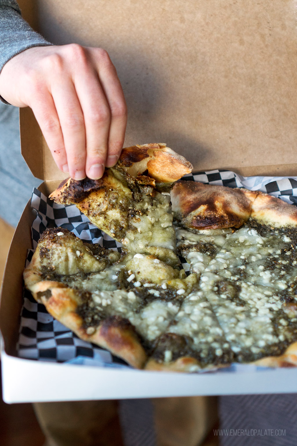 person picking up a mana'eesh flatbread, a popular Middle Eastern food in Seattle