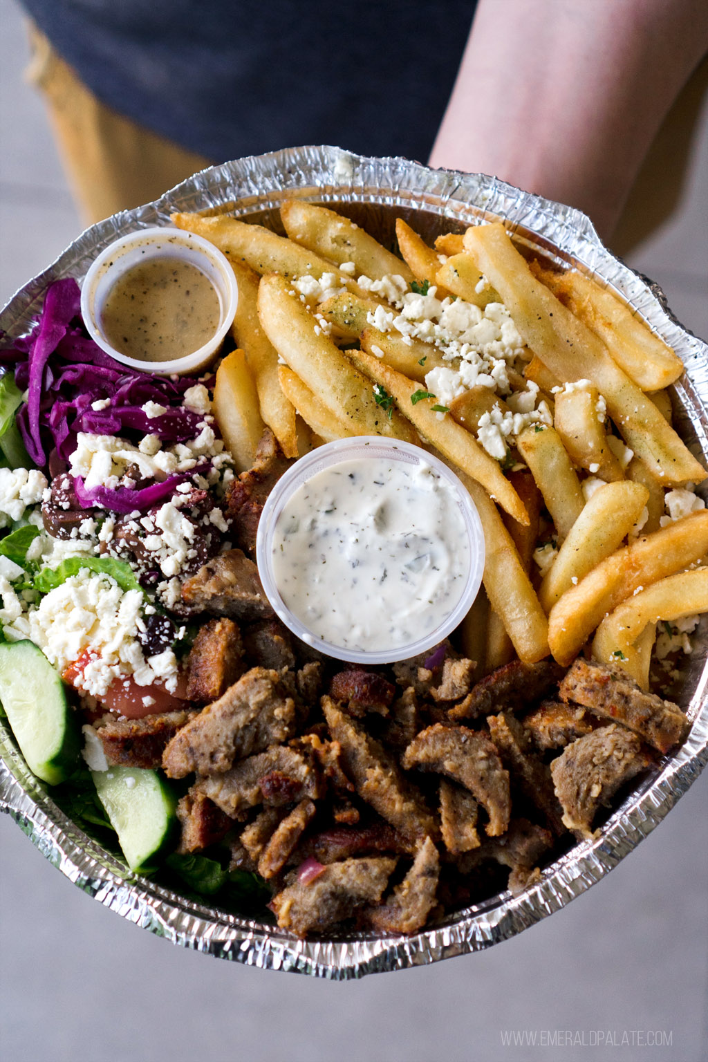 takeout container of Mediterranean food in Seattle: gyro meat, Greek fries, and salad.