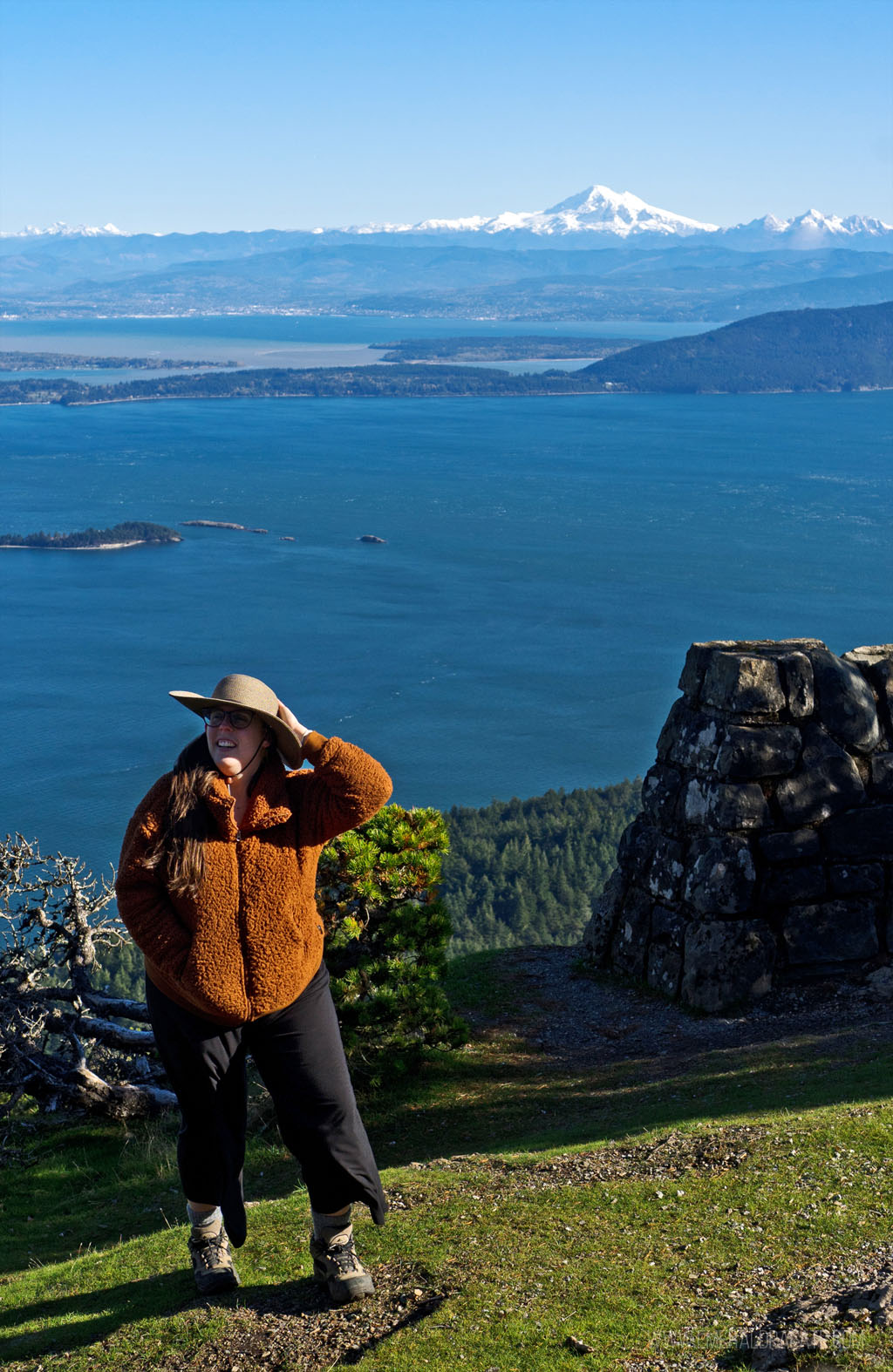 woman holding hat from the wind on the top of Mount Consitution