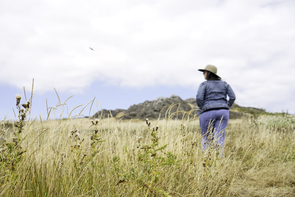 woman walking in grass on island, one of the best road trips from Seattle