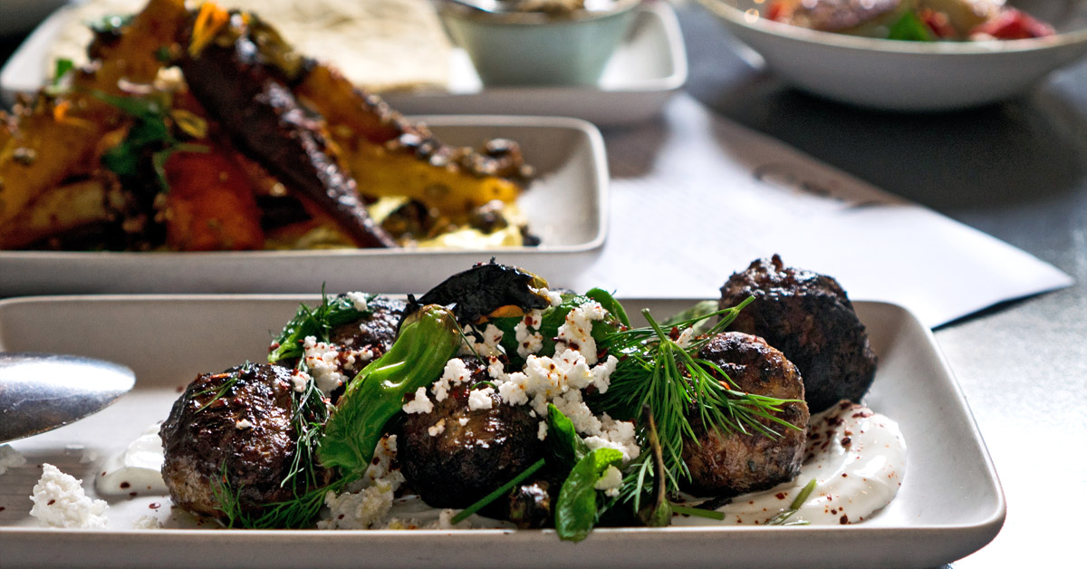 close up of lamb kofta meatballs on a table with other Mediterranean food