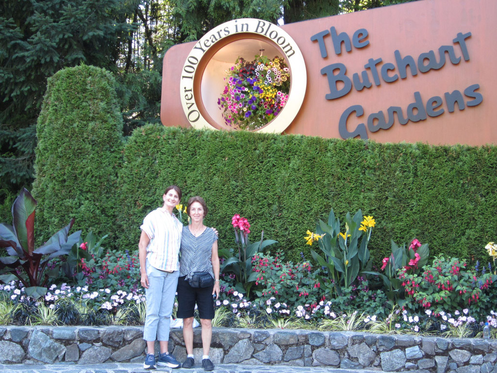 Two woman standing in front of The Butchart Gardens sign in Victoria BC