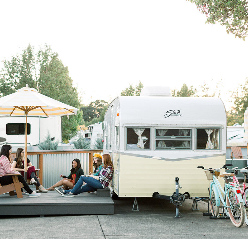 woman gathered outside a vintage trailer at a unique place to stay in Oregon
