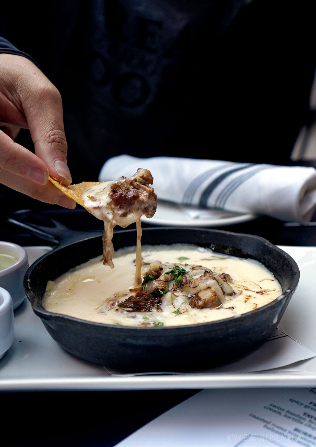 person picking up queso with a chip from a Eugene, Oregon restaurant