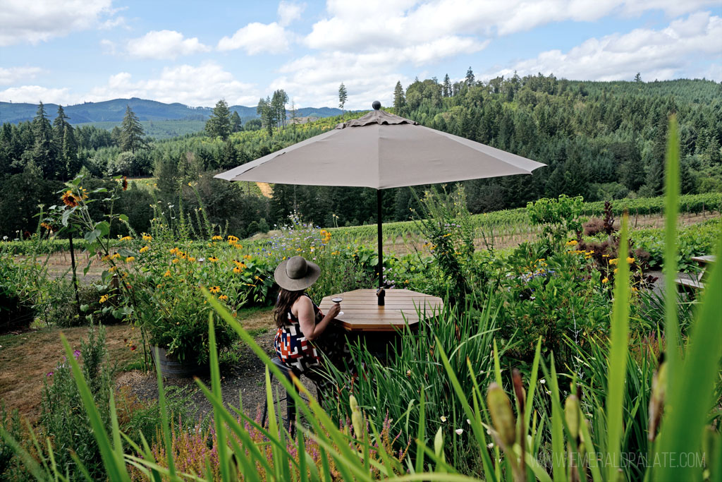 woman drinking wine in a garden at one of the best wineries in Eugene, OR