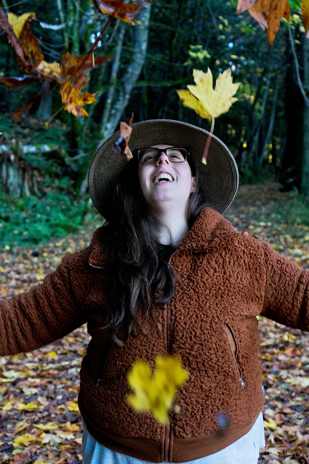 woman laughing at leaves fall on her