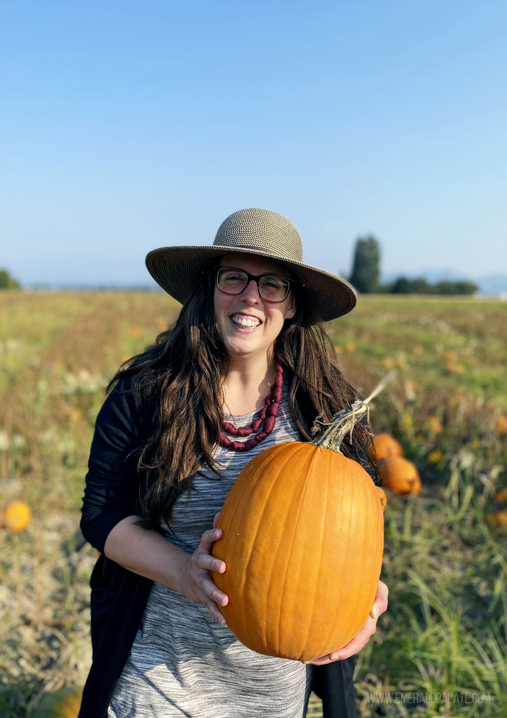 woman picking a pumpkin at a path, one of the best Halloween fun in Seattle