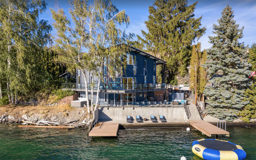 exterior photo of a lakeside retreat in Lake Chelan with a private dock, lounger chairs, and water trampoline