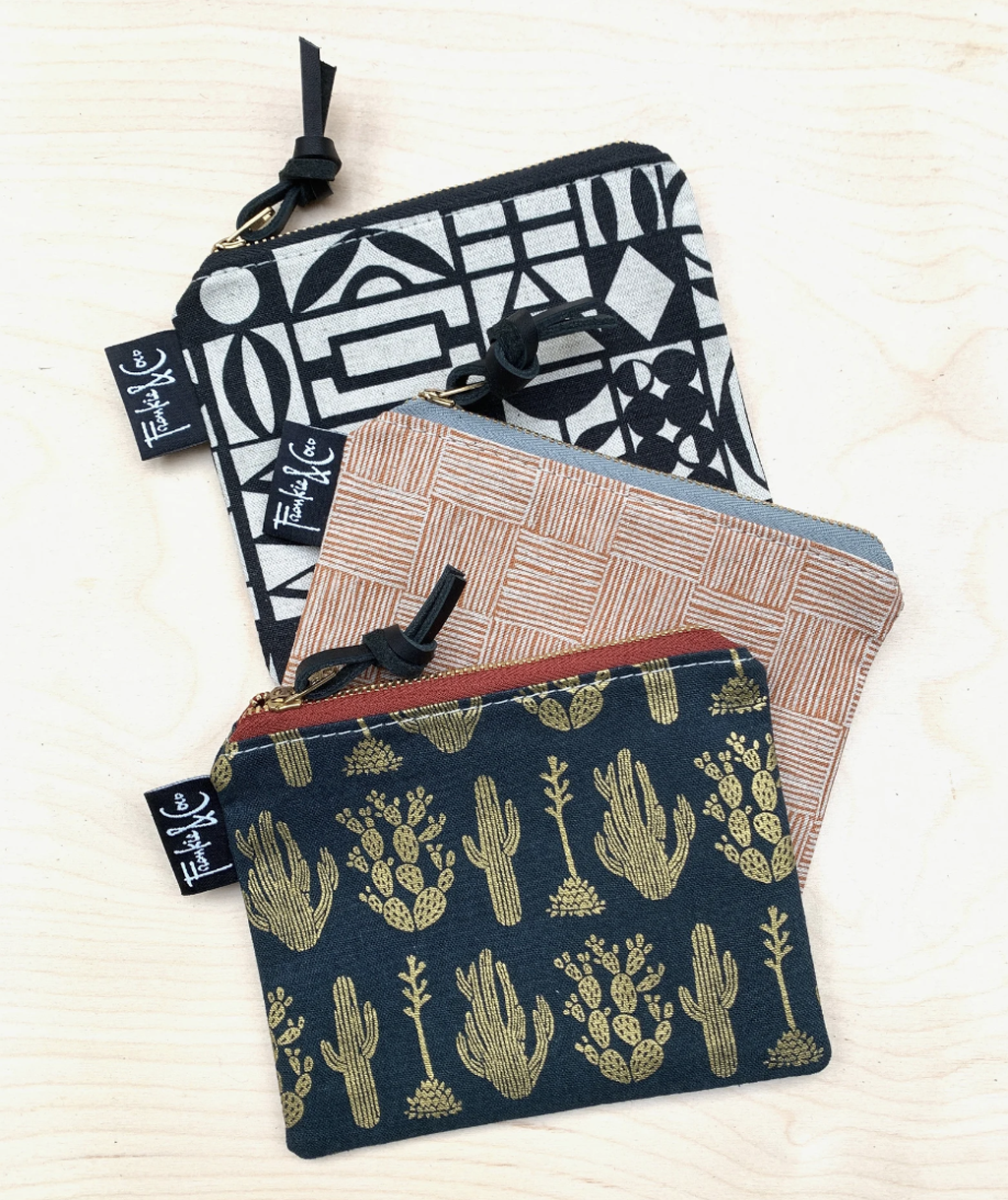 stack of three canvas zipper pouches in a cactus, striped checker, and geometric pattern