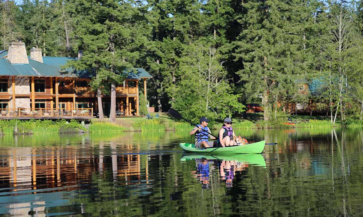 Couple kayaking with their dog in front of Lakedale Resort in Washington