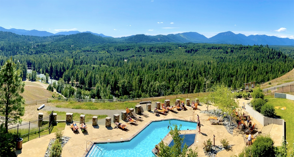 view of a hotel pool overlooking mountains dotted with evergreen trees