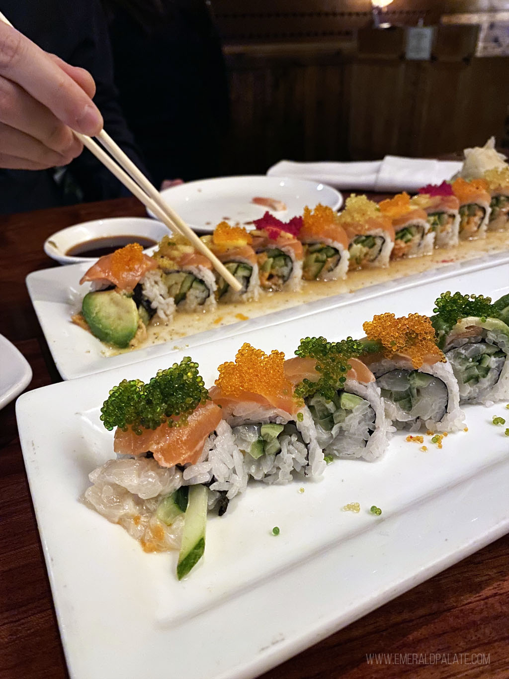 person picking up a sushi roll with chopsticks