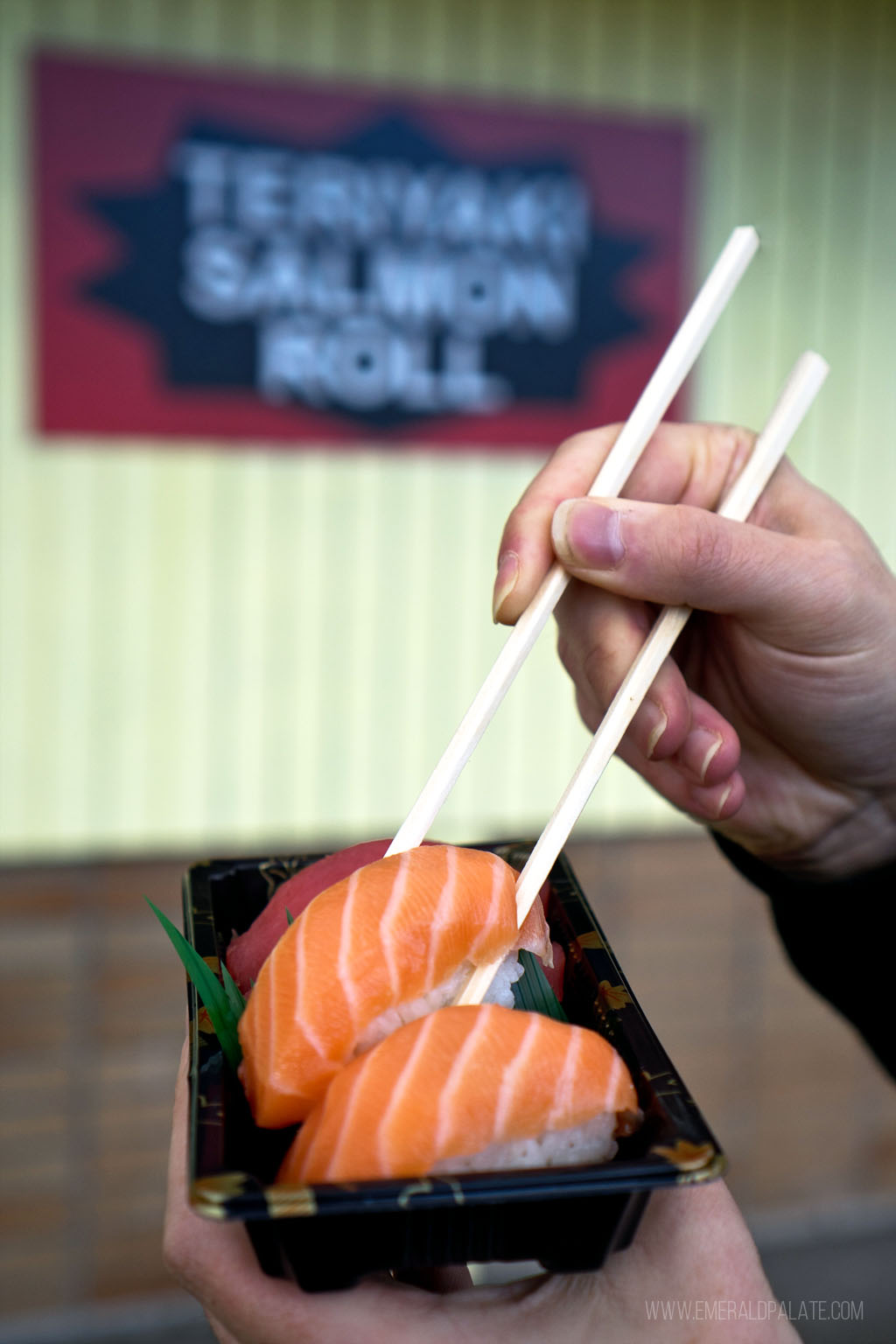 person picking up sake nigiri with chopsticks