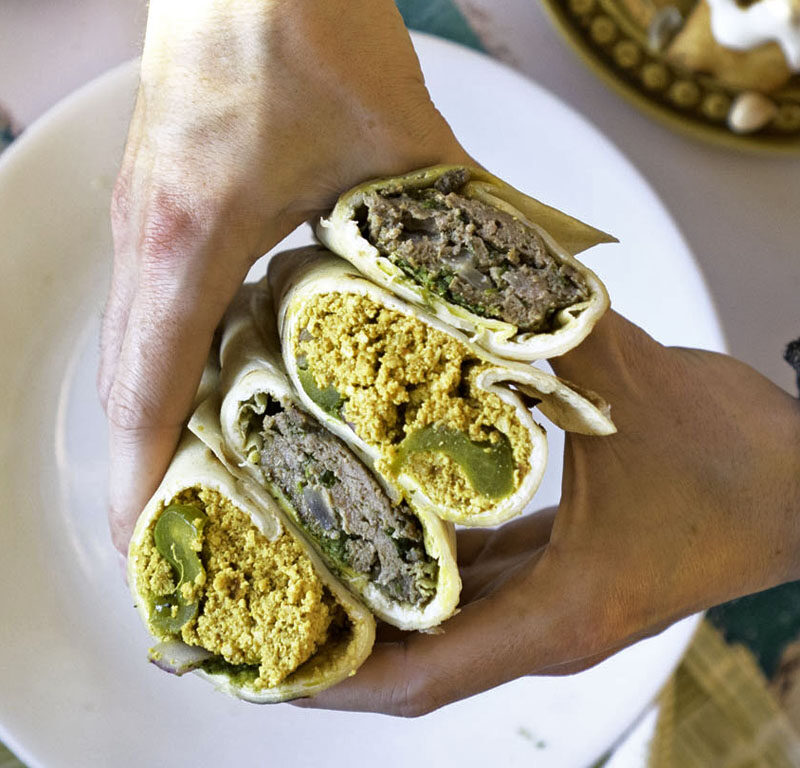 person holding stack of 4 kathi rolls from one of the best halal restaurants in Seattle