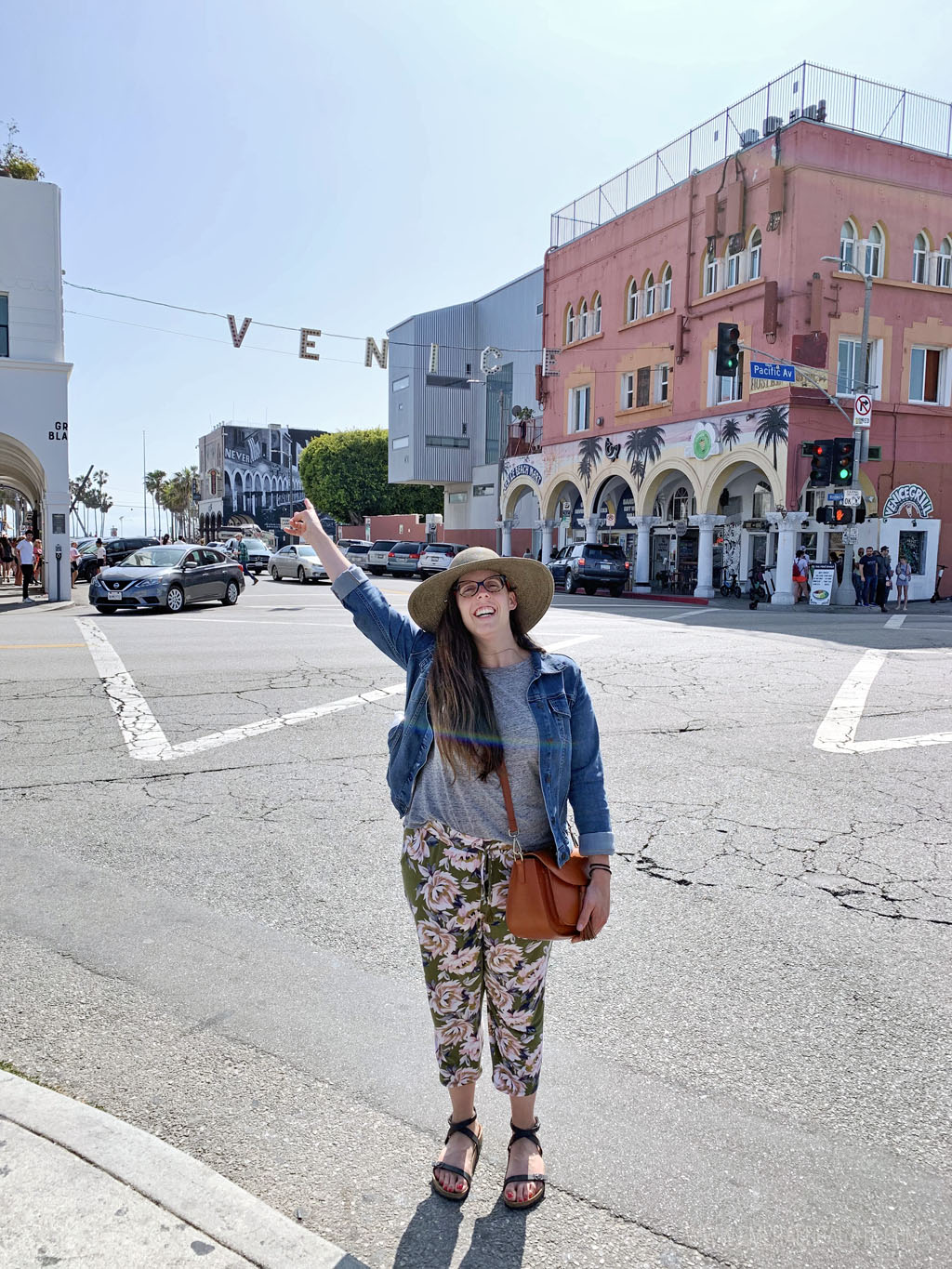 woman giving a peace sign in front of the famous Venice Beach sign