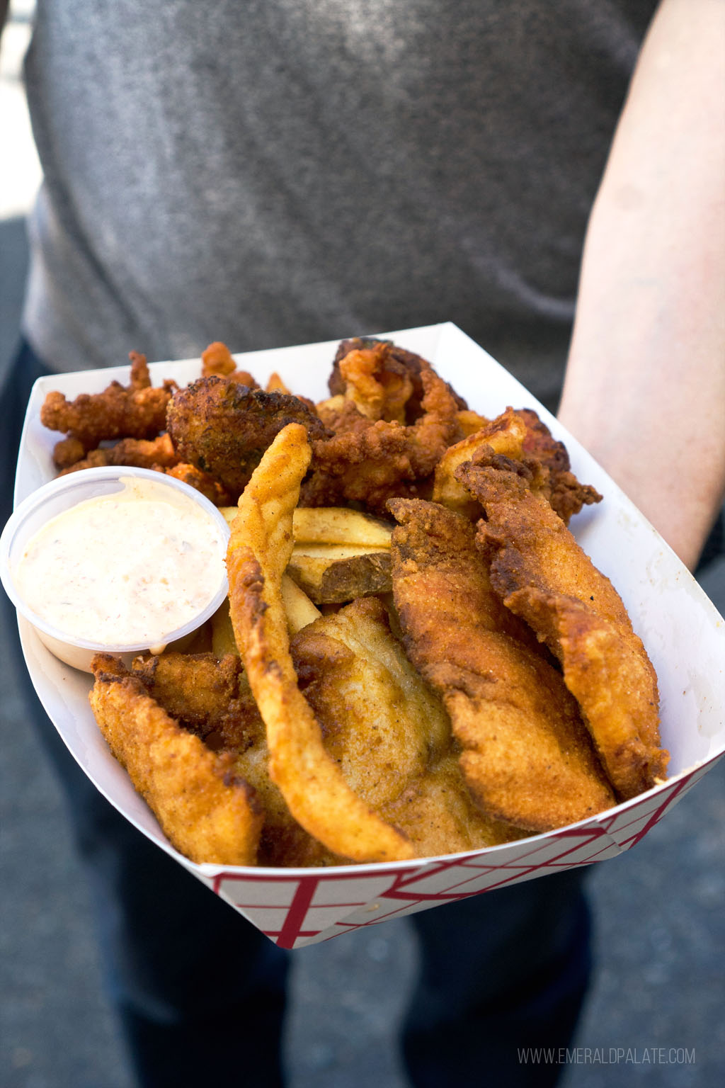person holding a takeout container of fried seafood with tartare sauce from one of the Black-owned Seattle restaurants