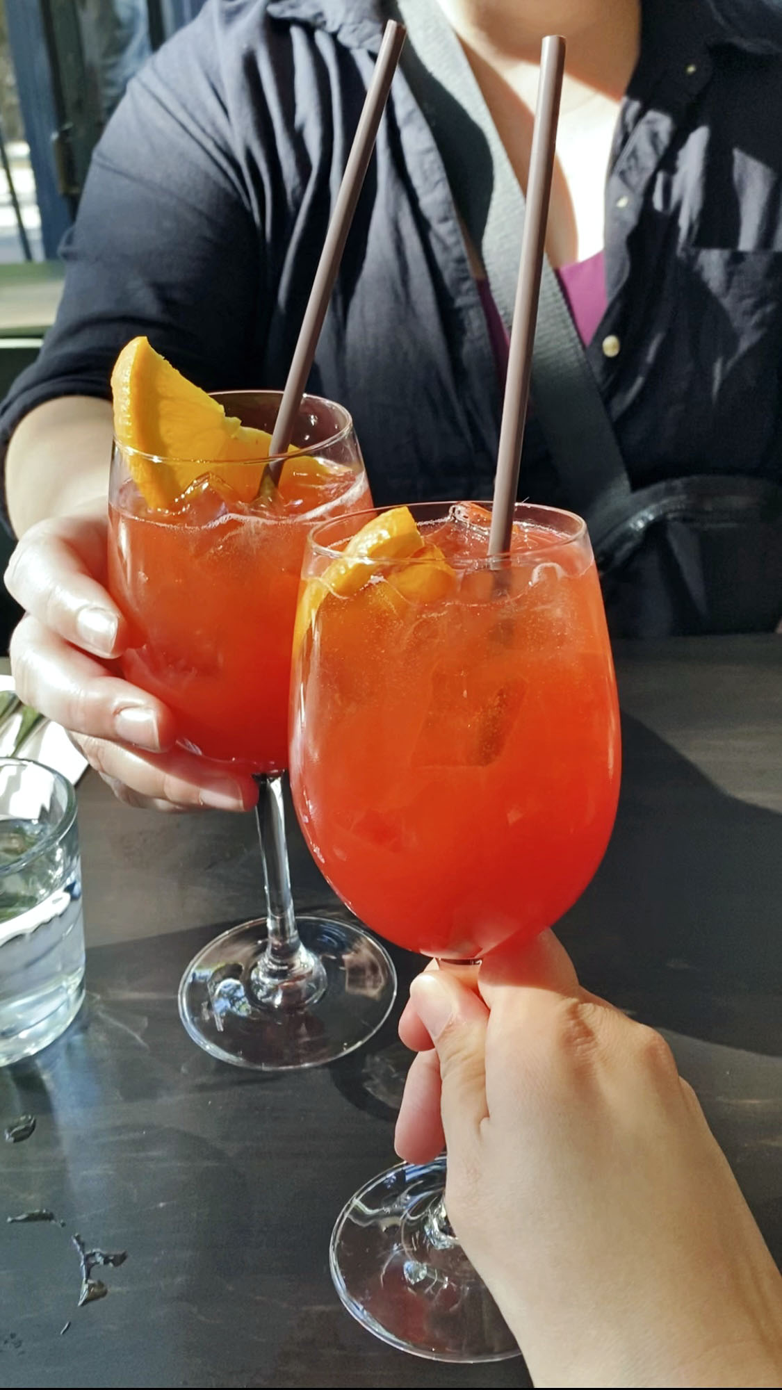 two people cheering aperol spritzes at a Seattle Italian restaurant