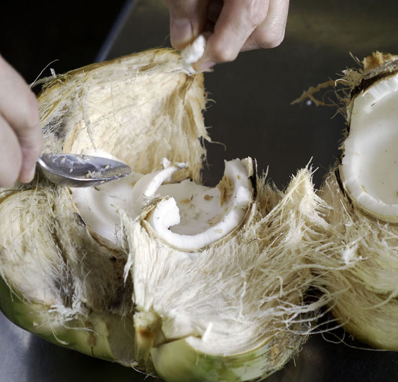 person breaking down a coconut, one of the best souvenirs from Maui