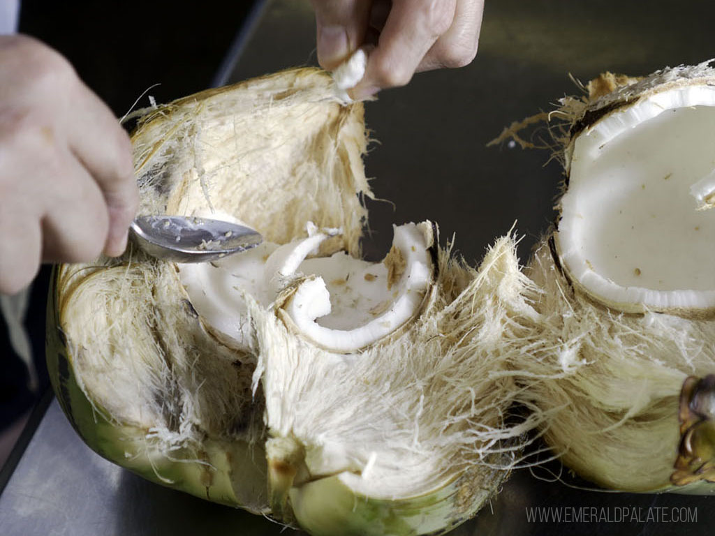 person cutting up a coconut, on of their souvenirs from Maui